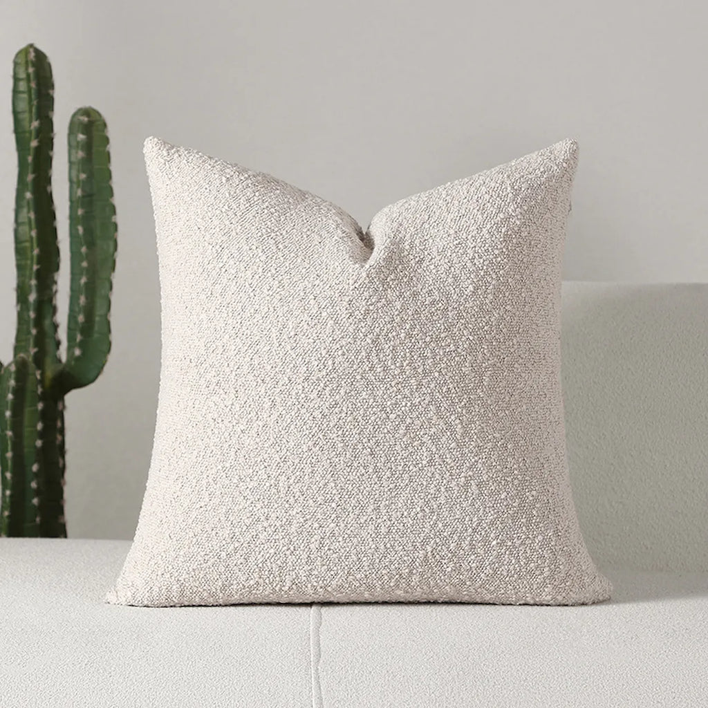 Textured beige pillow on a light gray sofa with a cactus plant in the background