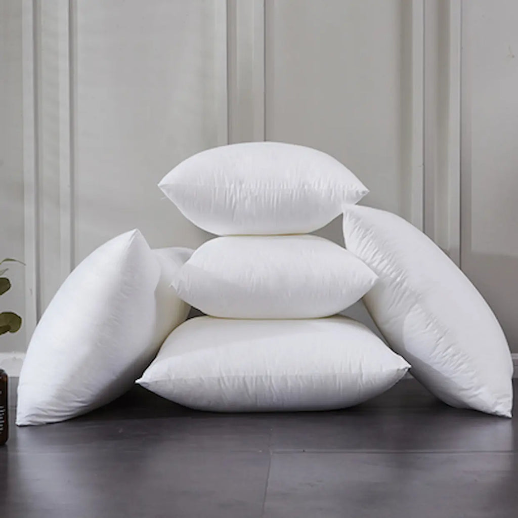 Stack of white pillows on a dark surface with a light gray wall in the background