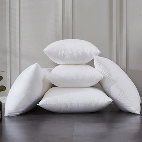 Stack of white pillows on a dark surface with a light gray wall in the background