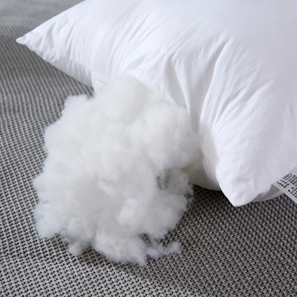 White pillow with fluffy stuffing on a gray textured surface