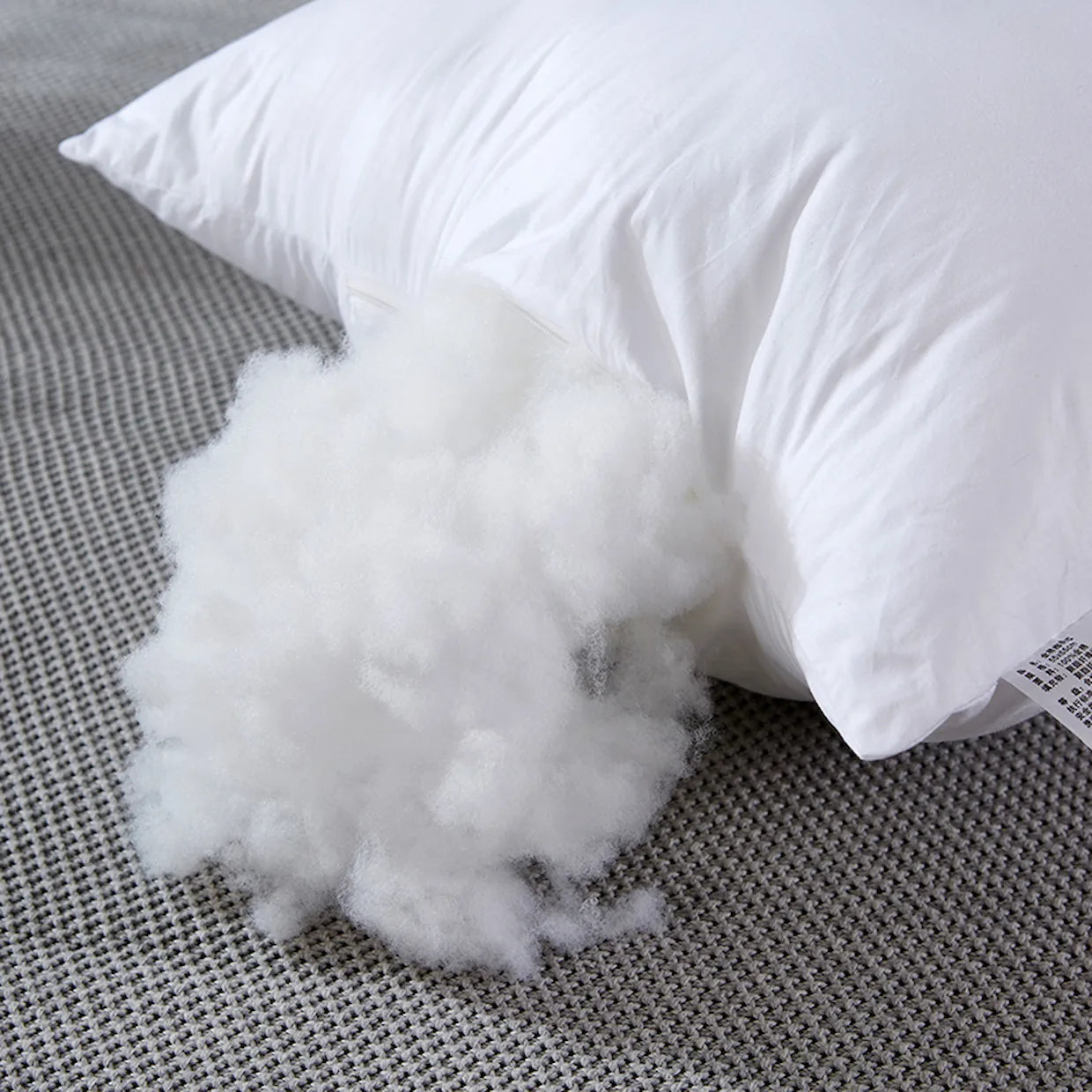 White pillow with fluffy stuffing on a gray textured surface