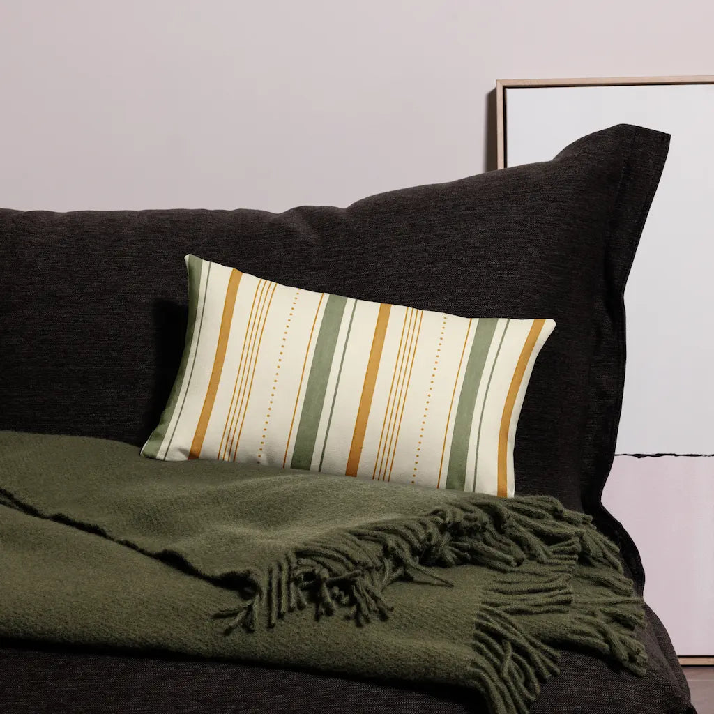 Striped pillow on a dark sofa with a green throw blanket